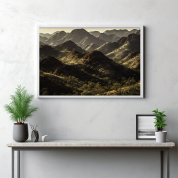 Ascend into the ethereal beauty of the MacDonnell Ranges with this panoramic depiction. The image showcases towering peaks and mountain ranges, punctuated by lush vegetation and set against the infinite wilderness. This isn't merely an outdoor view—it's a visual symphony of nature's grandeur, displaying the formidable allure of the mountains and the quiet strength of the Australian outback. Allow this image to transport you to new heights, where the grand spectacle of nature unfolds in all its glory.